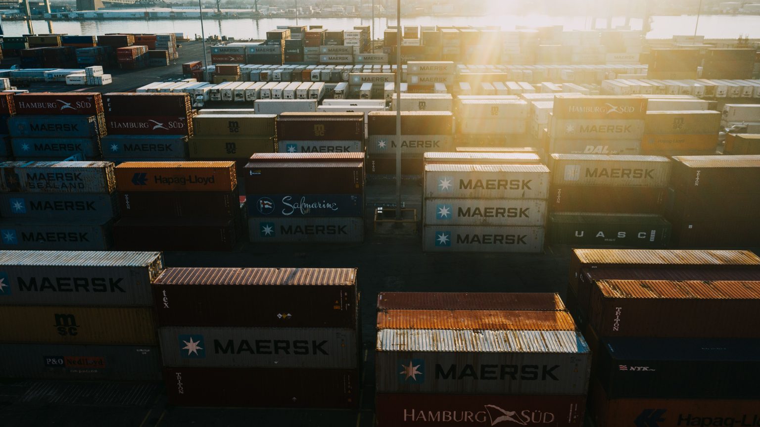 Shipping containers stacked at a port terminal at sunset
